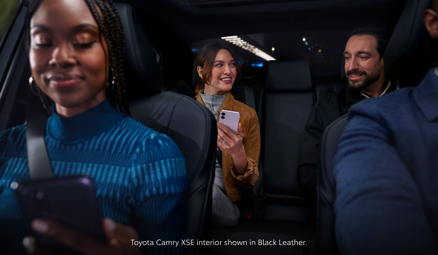 Interior view of passengers riding inside a 2026 Toyota Camry XSE featuring Black Leather seats and rear passenger legroom.