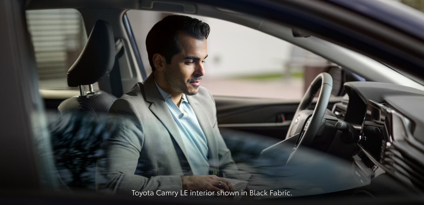 Side view through window of driver inside a 2026 Toyota Camry LE with Black Fabric seats.