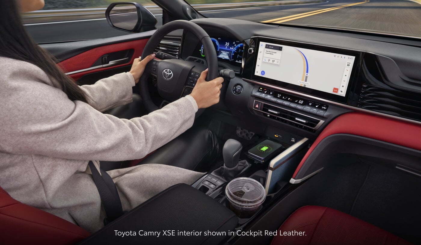 Interior view of a 2026 Toyota Camry XSE with Cockpit Red Leather seats, wireless smartphone charging, and digital navigation display.