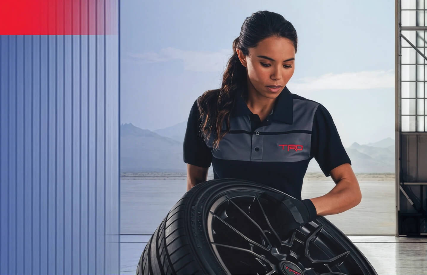 Close-up view of a Toyota TRD wheel with a technician rolling the tire inside a service bay.